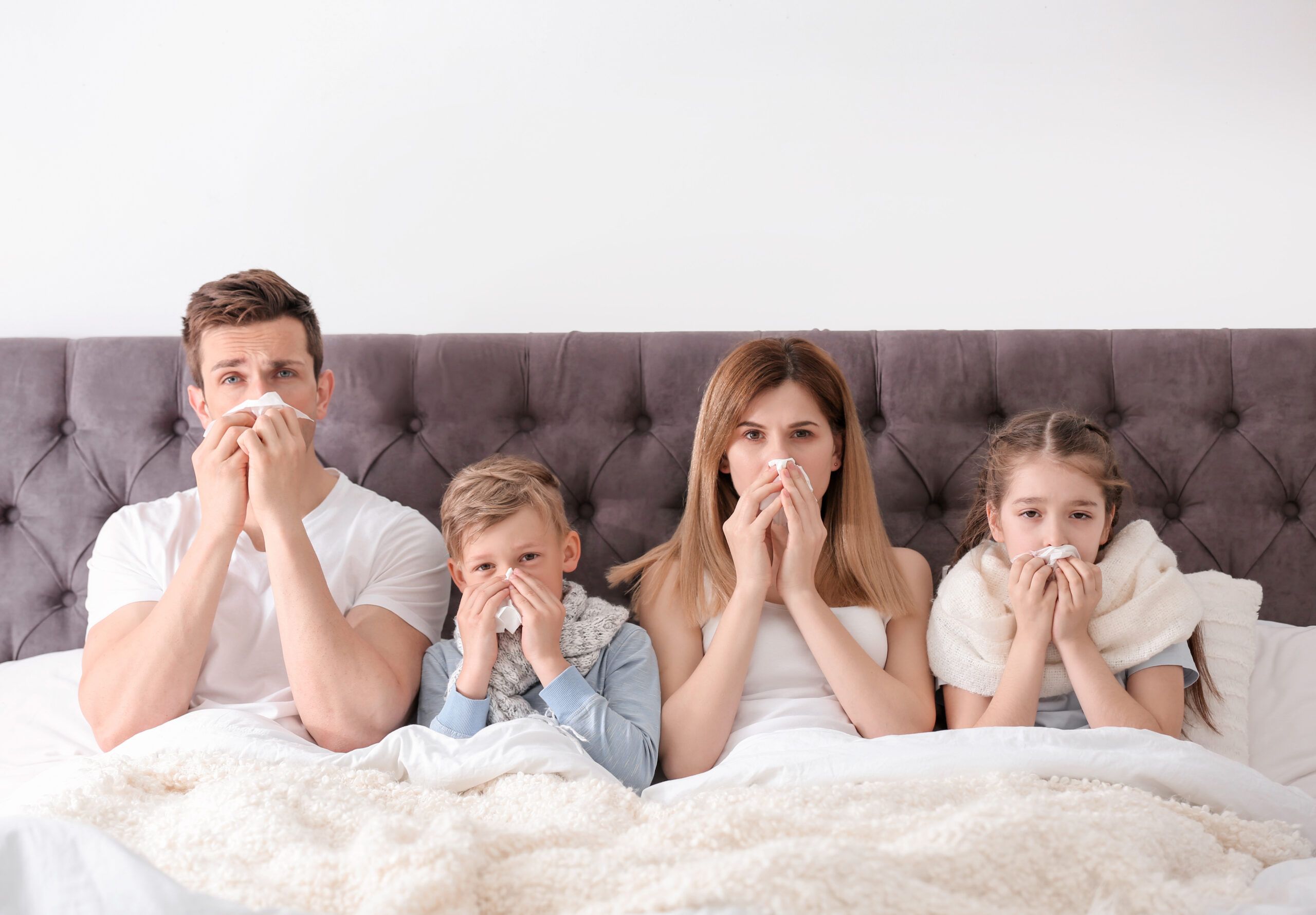 Family suffering from cold in bed at home