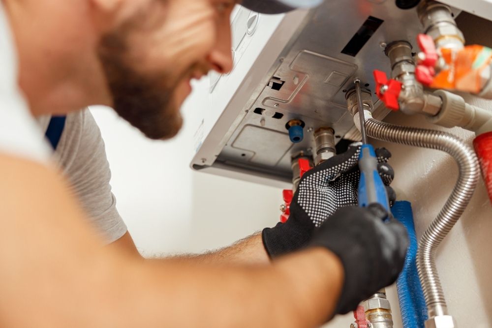 Closeup Of Plumber Using Screwdriver While Installing New Steel Hot Water Central Heating System