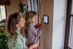 Girl,helping,mother,to,adjust,,lower,heating,temperature,on,thermostat.