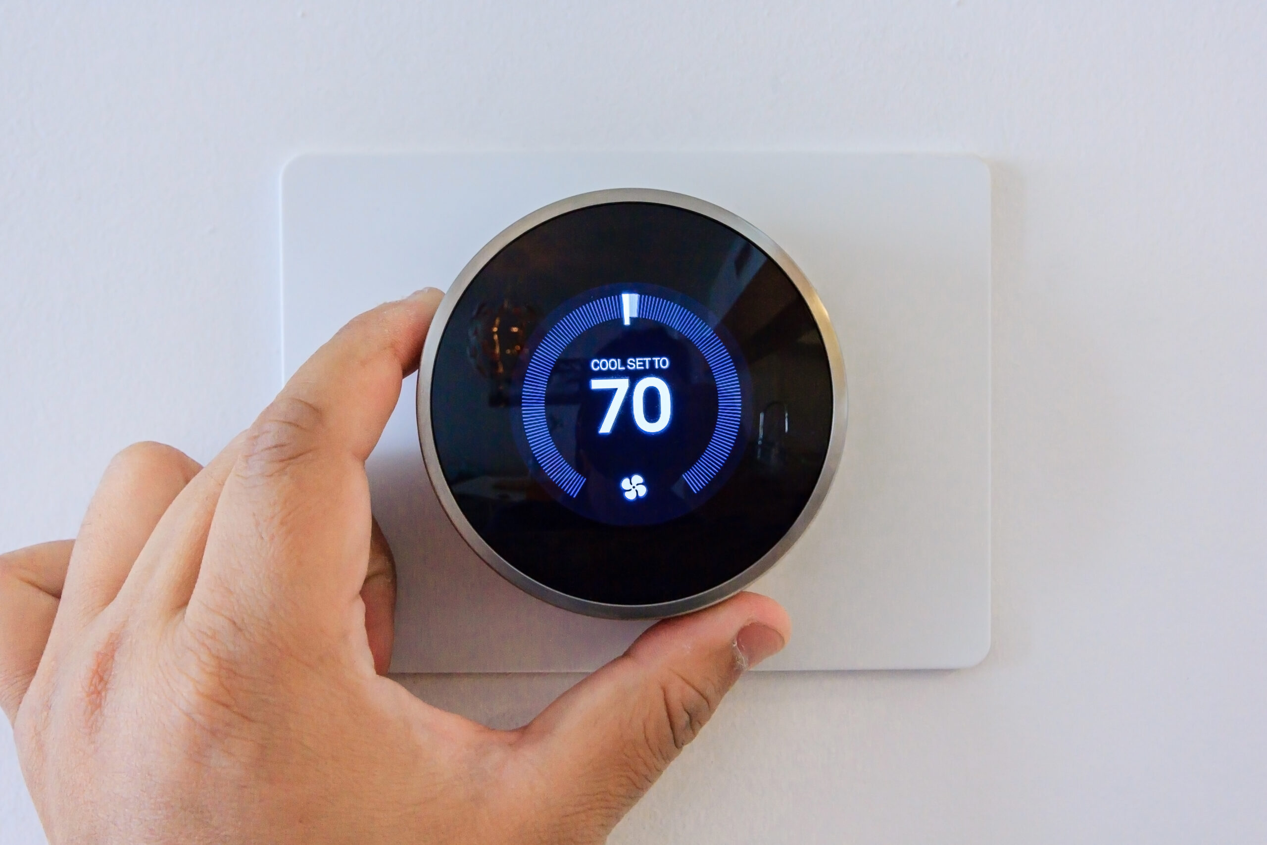 hands adjusting a smart thermostat